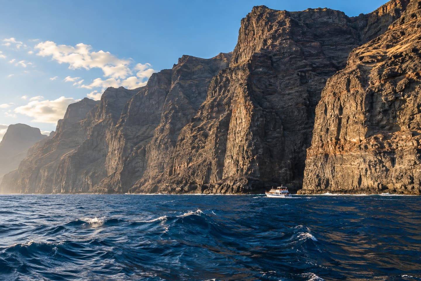 Ein Ausflugsboot fährt vor den hohen Basaltklippen von Los Gigantes.